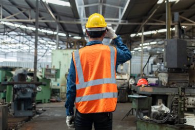 Arkadan bak. Mühendisler fabrikada tekdüze endüstri müteahhitleri giyerler. Fabrikada duran teknisyen makinesi..