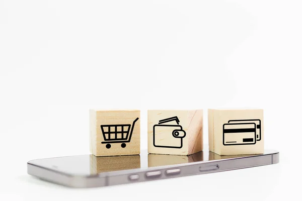 オンラインショッピングの概念 白い背景を持つスマートフォン上のショッピングや電子商取引アイコンを持つ木製のキューブブロック ビジネスオンラインマーケティング — ストック写真