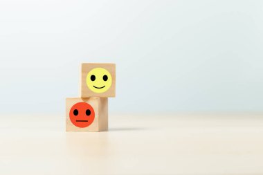 pozitif ve negatif duygularla yüzleş. Gülen suratlı tahta küp ve üzgün yüz ikonu. tatmin ve hizmet sıralaması.