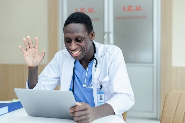 Male black African American doctor raising hand greet talking consultation online to patient in laptop. Office doing telemedicine services.Telemedicine medical concept.