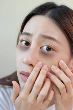 Asyalı genç bayan stres aynası geç saatlere kadar uykusuz kalmaktan dolayı koyu renk göz halkaları var. Sıkı çalışmaktan, uyumak için zaman yok..