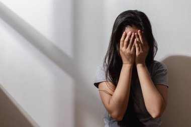 Depresyonda olan bir kadının elleri yerde tek başına otururken yüzünü kapatıyor. Dizlerini kucaklayan depresif bir kadın. mutsuz duygu.
