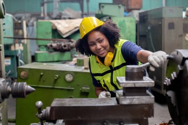 Teknisyen ağır sanayi kavramı, Afrika kökenli Amerikalı kadın mühendis fabrikada çalışırken başlık takıyor. Kadın teknisyen kontrol metali endüstriyel torna. 