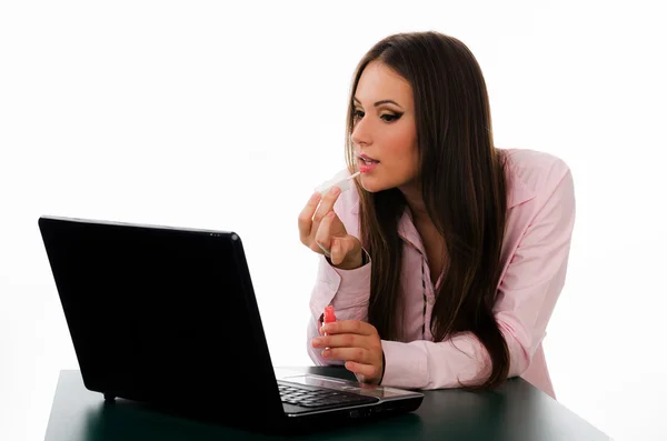 Retrato de uma mulher de negócios colocando em brilho labial usando sua tela de laptops como um espelho — Fotografia de Stock