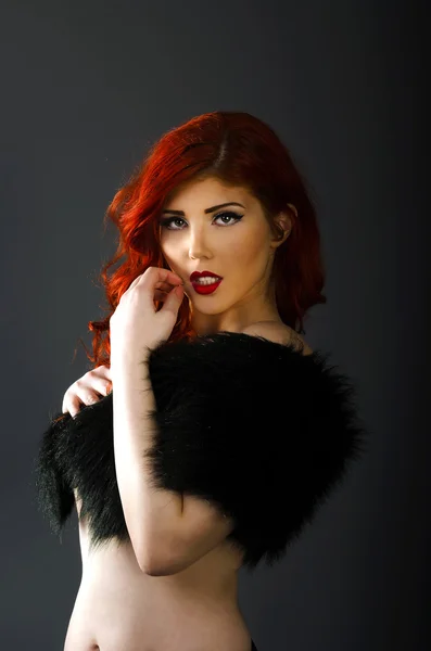 Topless redhead woman covering her breasts with a black fur coat — Stock Photo, Image