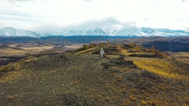 Lány turista fehér ruhában a hegyekben. Kilátás a havas csúcsokra. Légfelülnézet — Stock videók