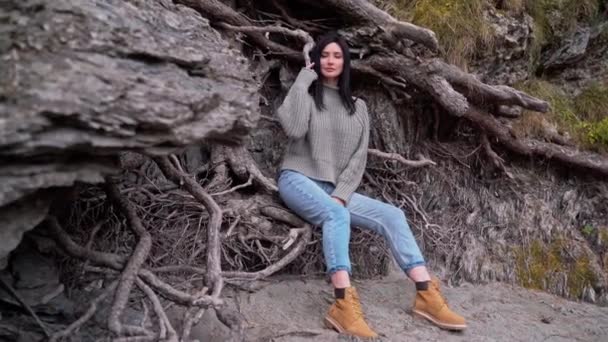 Beautiful girl tourist photo session near tree. Look into camera Autumn yellow trees rocks roots — Stock Video