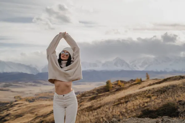 Schöne stilvolle Touristin posiert vor dem Hintergrund weißer Schneegipfel. Sonnig — Stockfoto