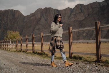 Esmer Avrupalı bir kız, yol boyunca dağların arkasında yürüyor. Vahşi Batı. Sonbahar