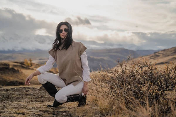 Krásná stylová dívka pózující na pozadí bílých zasněžených vrcholků. Portrét. Vítr Royalty Free Stock Fotografie