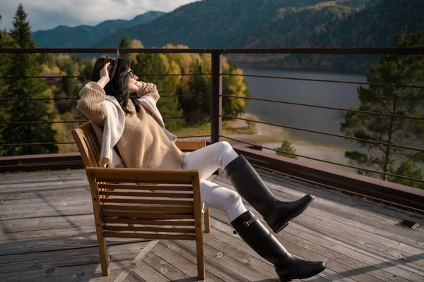 Belle fille dans des vêtements légers élégants et chapeau brun se trouve sur le toit dans les rayons de soleil et de froid — Photo