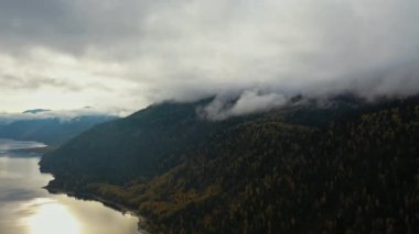 Gün batımında göl. Sonbahar sarı ağaçları. Dağlar. Havadan üst görünüm
