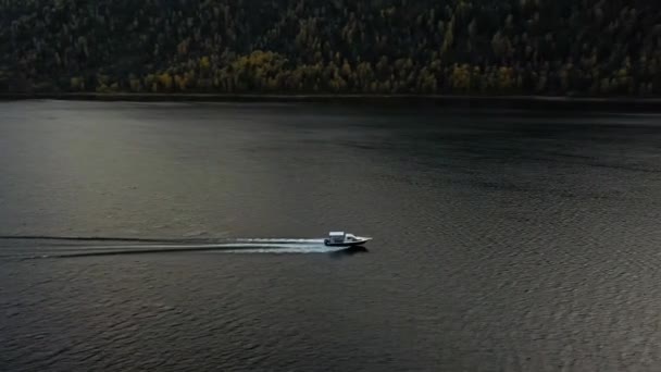 Лодка плывет на высокой скорости через воду. Озеро на закате. Вид сверху с воздуха — стоковое видео