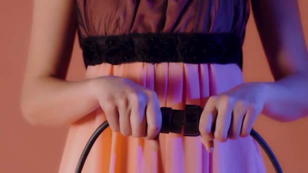Parlak arka planı olan güzel elbiseli bir kız elektrik prizine bağlanıyor ve fişe takılıyor. — Stok video