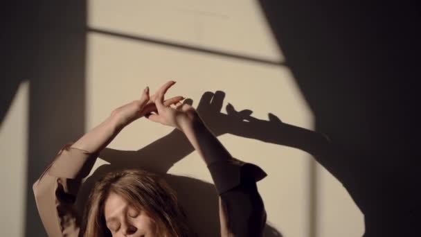 Beautiful European girl in a silk shirt in the sun raises her hands up — Stock Video