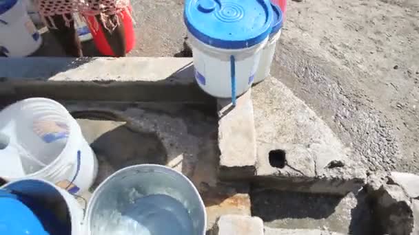 Panning shot of buckets being filled at well. — Stock Video