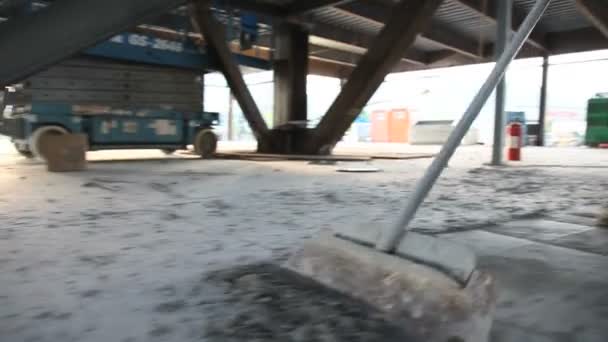 Low drifting shot of man scraping cement off floor. — Stock Video