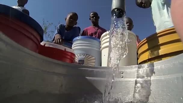 Port au prince, haiti - 17. Dezember 2013: Unbekannte beobachten, wie Wasser Eimer am Brunnen am Stadtrand von port au prince, haiti füllt. (nur für redaktionelle Zwecke.) — Stockvideo