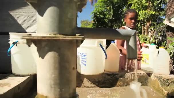 PORT AU PRINCE, HAÏTI - 17 DÉCEMBRE 2013 : Une jeune fille non identifiée remplit une cruche à un puits dans la banlieue de Port au Prince, en Haïti. (Pour usage rédactionnel seulement .) — Video