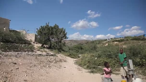 PORT AU PRINCE, HAITI - DEZEMBRO 17, 2013: Pessoas não identificadas bombeando água em poço nos arredores de Porto Príncipe, Haiti. (Apenas para uso editorial .) — Vídeo de Stock