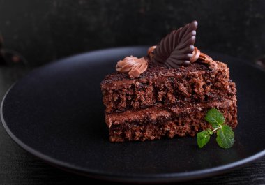 Nane şekeriyle süslenmiş siyah bir arka planda bir tabak çikolatalı kek..