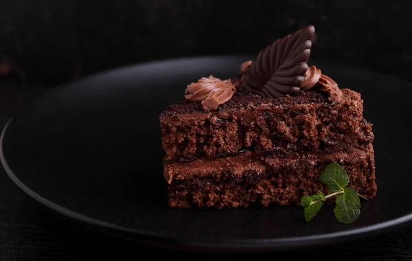 Κομμάτι Κέικ Σοκολάτας Ένα Πιάτο Μαύρο Φόντο Διακοσμημένο Μέντα — Φωτογραφία Αρχείου