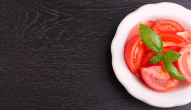 Eskimiş arka planda beyaz tabakta fesleğen ve peynirli domates salatası. Üst görünüm.