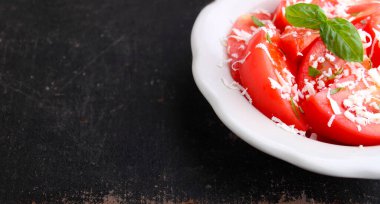 Eskimiş arka planda beyaz tabakta fesleğen ve peynirli domates salatası..