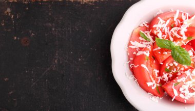 Eskimiş arka planda beyaz tabakta fesleğen ve peynirli domates salatası. Üst görünüm.