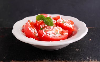 Eskimiş arka planda beyaz tabakta fesleğen ve peynirli domates salatası..