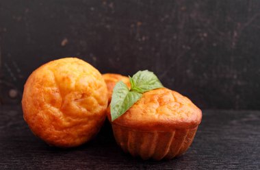 Fesleğenle süslenmiş siyah arka planda peynirli kekler..