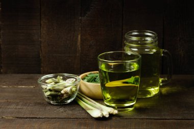 Bardakta limon çayı ve ahşap zeminde taze limon çimi. Sağlıklı bitkisel içecek konsepti..