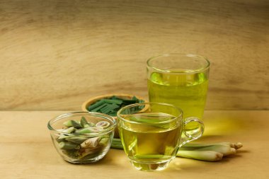 Bardakta limon çayı ve dilimlenmiş taze limon otu ve ahşap arka planda yeşil yaprak. Sağlıklı bitkisel içecek kavramı.