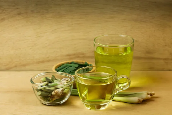 Bardakta limon çayı ve dilimlenmiş taze limon otu ve ahşap arka planda yeşil yaprak. Sağlıklı bitkisel içecek kavramı.