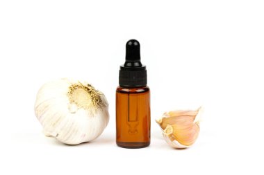Şişede sarımsak yağı ve beyaz arka planda taze sarımsak..