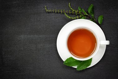 Tulsi ya da beyaz fındıklı kutsal fesleğen çayı. Taze tütsü dalı ve siyah ahşap arka plan manzaralı yaprak. Hindistan 'da Ayurvedic tıp.