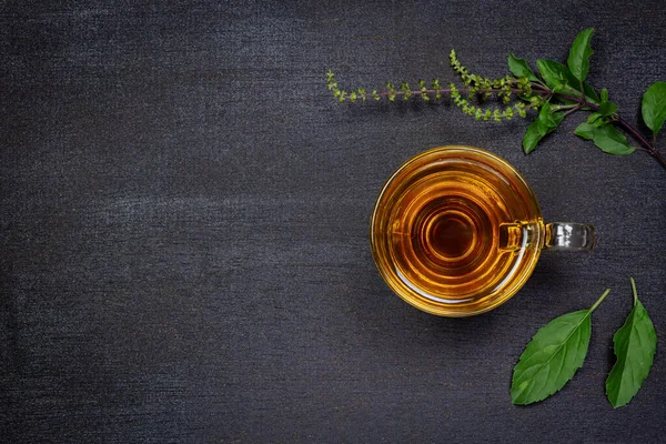 Tulsi ya da şeffaf cam bardakta kutsal fesleğen çayı ve ahşap arka planda taze tütsü yaprağı. Hindistan 'da Ayurvedic tıp.
