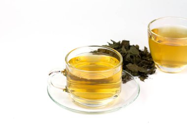 Tulsi ya da şeffaf bardaktaki kutsal fesleğen çayı ve beyaz arka planda izole edilmiş kurumuş tül yaprağı yığını. Hindistan 'da Ayurvedic tıp. Sağlık için iç..