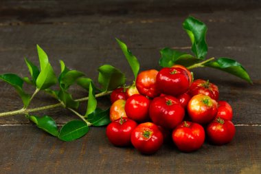 Ahşap arka planda dalı olan Acerola Cherry veya Barbados Cherry Yığını.