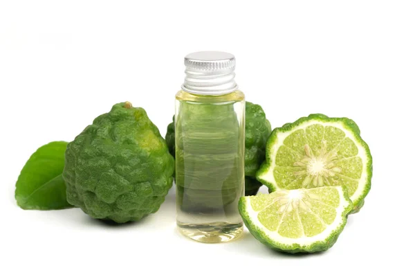 Şişede Bergamot yağı ve beyaz arka planda yeşil yapraklı taze bergamot meyvesi..