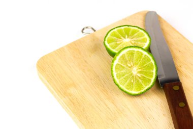 Kaffir kireç meyvesi ya da ikiye bölünmüş Bergamot bıçağı beyaz arka planda izole edilmiş ahşap kesme tahtasına yerleştirilir..