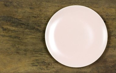 Ahşap kırsal masada boş pembe seramik tabak..