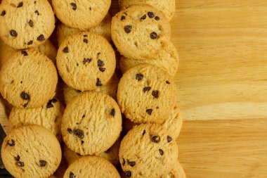 Kırsal ahşap arka planda çikolata parçacıklı kurabiye yığını.