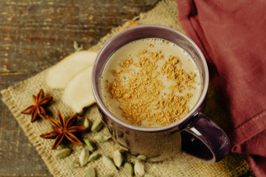 Zencefilli bir fincan Masala çayı, kakule ve ahşap arka planda anason. Masala chai popüler geleneksel Hindistan içeceği süt, çay ve baharattan yapılmıştır..