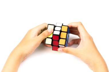 SAMUT-SAKHON, THAILAND - Nisan 02, 2021: Rubik küp bulmacasını çözmeye çalışan genç bir kızın elleri.