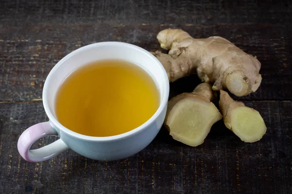 Seramik fincanda zencefil çayı ve ahşap arka planda dilimlenmiş taze zencefil. Bilimsel adı zingiber officinale. Sağlık hizmetleri konsepti için bitkiler.