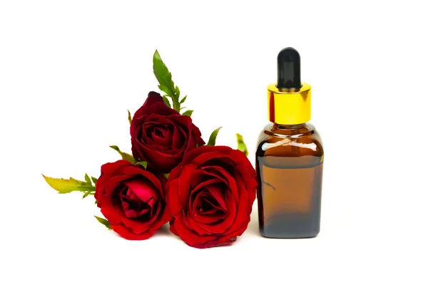 白い背景に赤いバラの花を孤立させたガラス瓶の中のバラ油 エッセンシャルオイル製品コンセプト — ストック写真