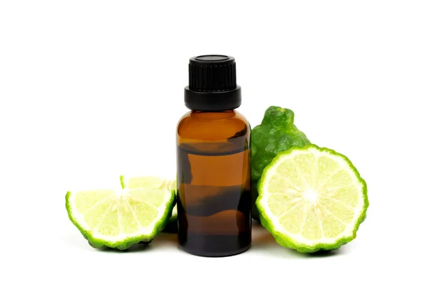 Şişede Bergamot yağı ve beyaz arka planda yeşil yapraklı taze bergamot meyvesi..