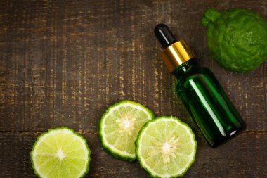 Şişede Bergamot yağı ve kırsal ahşap arka planda taze bergamot meyvesi..