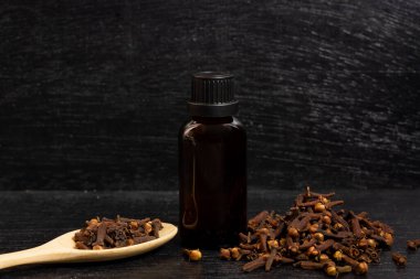 Şişe içindeki karanfillerin temel yağı ve ahşap kaşık üzerindeki kuru karanfiller..